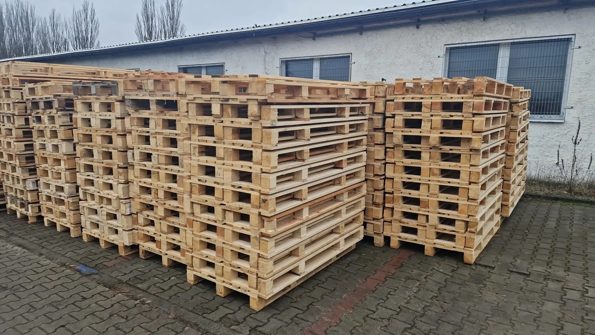 Stos palety drewnianych przed budynkiem